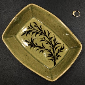 May include: A rectangular ceramic dish with a green glaze and a black floral design.