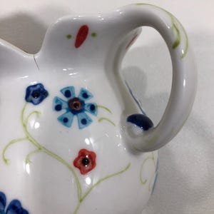 Puede incluir: Una taza de cer&aacute;mica blanca con un asa negra y el texto "But First, Coffee" en negro y negrita. La taza est&aacute; sobre una superficie blanca. La taza mide aproximadamente 10 cm de alto.