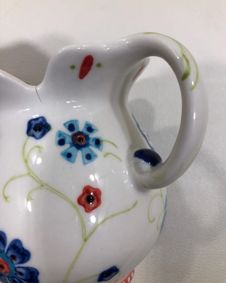 Puede incluir: Una taza de cer&aacute;mica blanca con un asa negra y el texto "But First, Coffee" en negro y negrita. La taza est&aacute; sobre una superficie blanca. La taza mide aproximadamente 10 cm de alto.