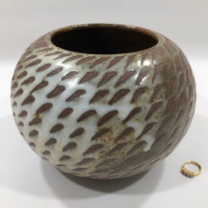 May include: A brown ceramic bowl with a white glaze and a textured pattern. The bowl is round and has a wide opening.