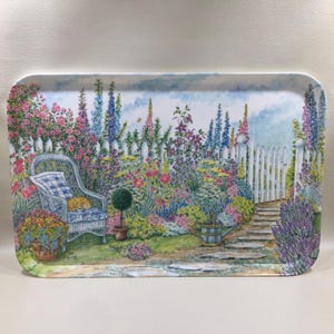 May include: A rectangular serving tray featuring a watercolor illustration of a garden scene with a white picket fence, a wicker chair with a blue and white cushion, a sleeping orange cat, a metal watering can, and colorful flowers.
