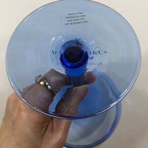 May include: Blue glass goblet with a stem and a wide base. The base has a sticker that reads "Made in China, Fabriqu&eacute; en Chine, Hand Wash Only, Not Microwave Safe" and "Mark &  Spikes, Anthropologie".