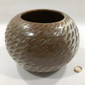 以下が含まれることがあります： 白釉薬がかけられた茶色の丸い陶器の花瓶。花瓶は開口部が広く、丸い底をしています。
