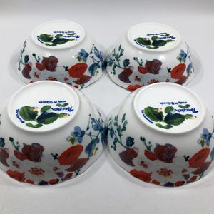 May include: Four white porcelain bowls with a floral design. The bowls feature a pattern of red, blue, and green flowers and foliage. The bottom of each bowl has a green and blue floral design and the text "Porcelain made in Sweden".