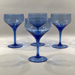 May include: Set of four cobalt blue glass stemmed cocktail glasses. The glasses have a wide bowl and a long, thin stem.