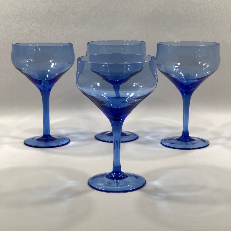 May include: Set of four cobalt blue glass stemmed cocktail glasses. The glasses have a wide bowl and a long, thin stem.