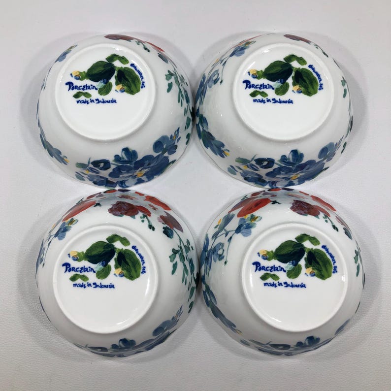 May include: Four white porcelain bowls with floral designs in blue, red, and green. The bowls have a rounded shape and are decorated with flowers and leaves. The text "Porcelain made in Indonesia" is printed on the bottom of each bowl.