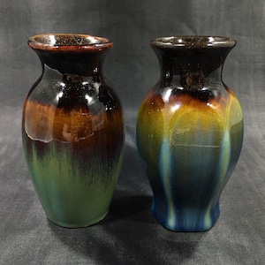 May include: Two ceramic vases with a crackled glaze finish. The vase on the left is green, brown, and black. The vase on the right is blue, yellow, and brown.