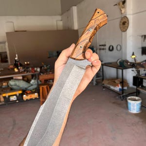 outdoor chopper blade with wide profile and stonewashed finish held above wooden background