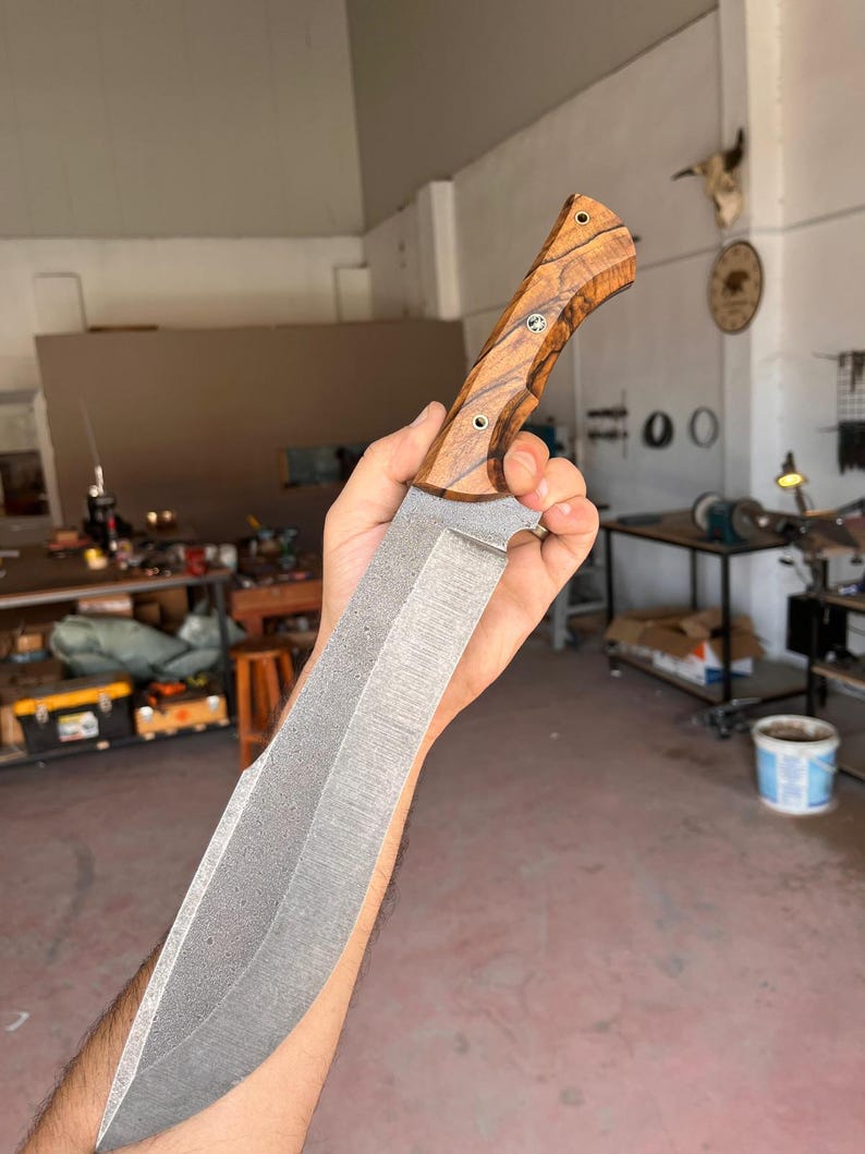 outdoor chopper blade with wide profile and stonewashed finish held above wooden background