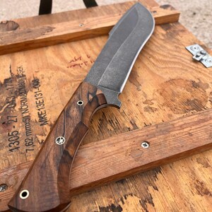 handmade machete with walnut wood handle resting on warrior style shoulder carry leather sheath