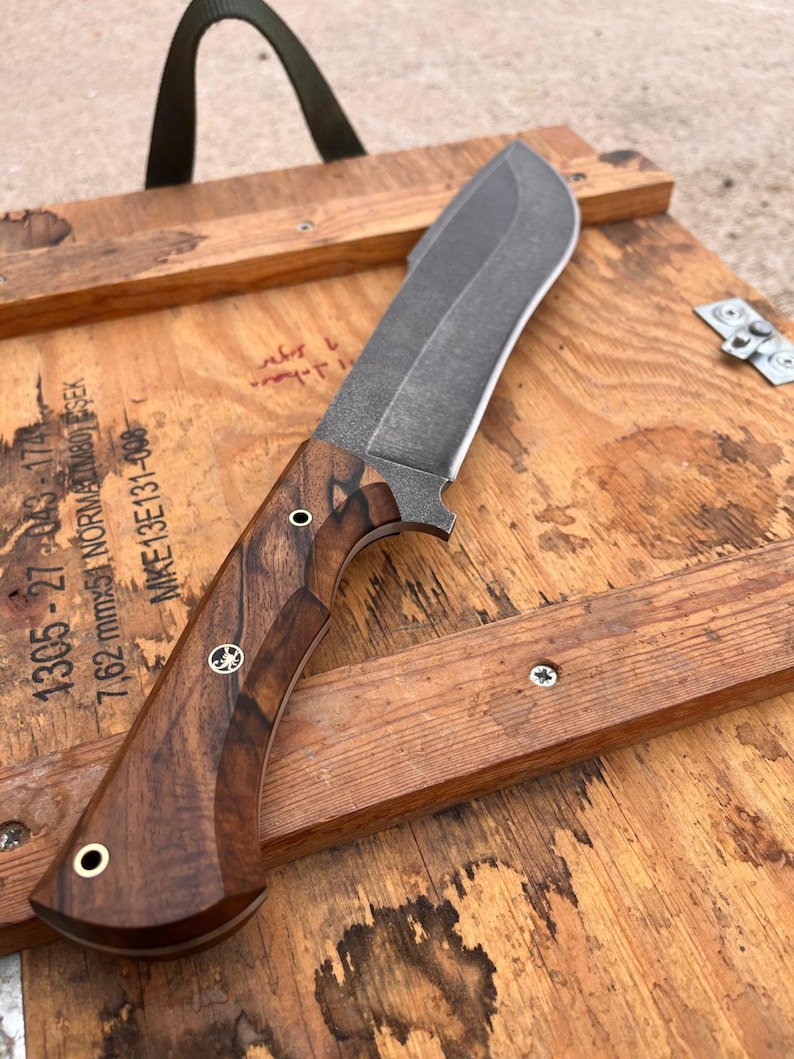 handmade machete with walnut wood handle resting on warrior style shoulder carry leather sheath