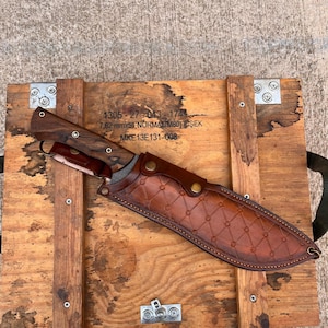 walnut handled machete with long cutting edge displayed outdoors on rustic wooden planks