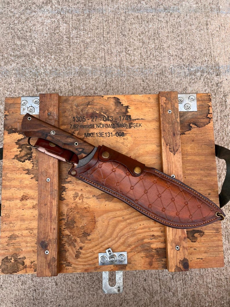 walnut handled machete with long cutting edge displayed outdoors on rustic wooden planks