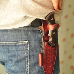 Knife partially sheathed showing accurate fit and exposed handle.