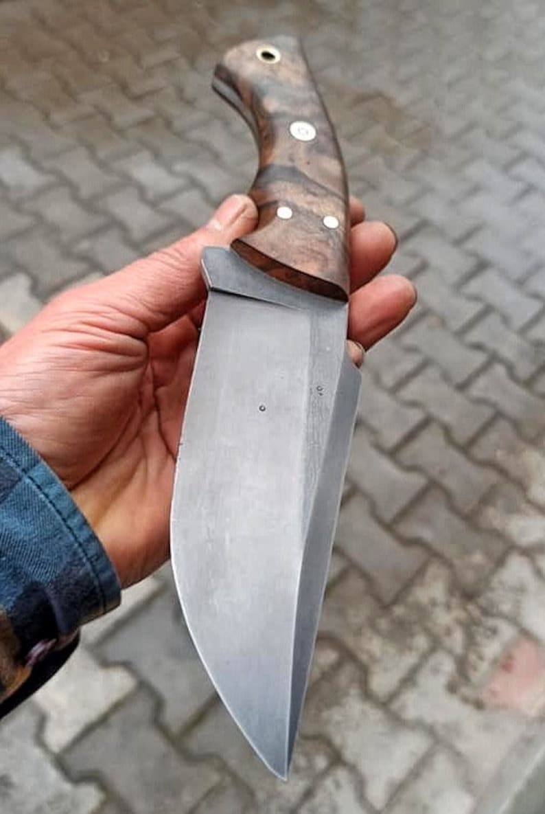 Outdoor style presentation of knife and sheath on textured natural background.
