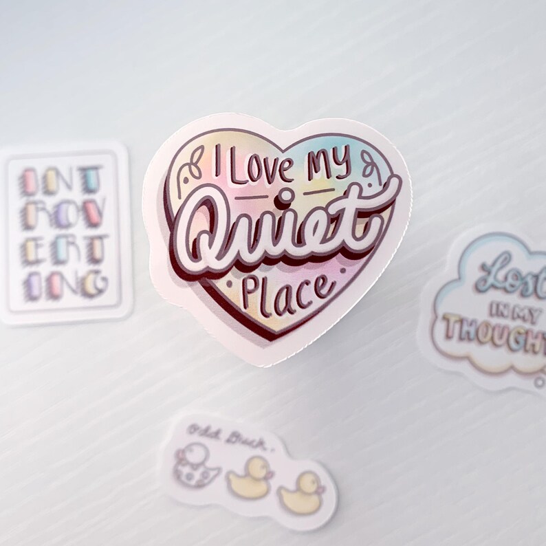 May include: A heart-shaped sticker with a rainbow gradient design. The sticker says "I Love My Quiet Place" in a whimsical font.