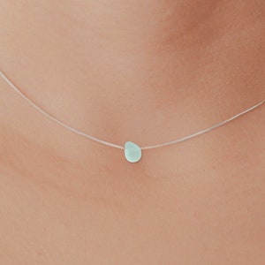 May include: A delicate silver chain necklace with a single light blue teardrop-shaped pendant.