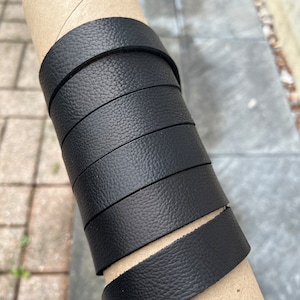 May include: A roll of black leather with a textured surface. The leather is wrapped around a cardboard tube.