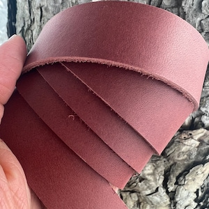 May include: A close-up of a roll of dark red leather. The leather is smooth and has a slight sheen.