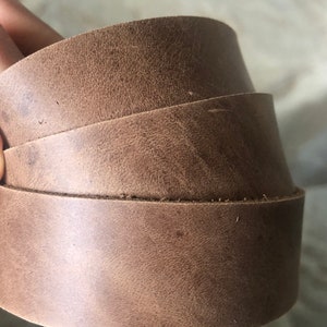 May include: Three pieces of brown leather straps stacked on top of each other.