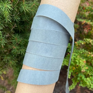 May include: A roll of light blue leather cord, wrapped around a cardboard tube. The cord is smooth and has a slightly textured surface.