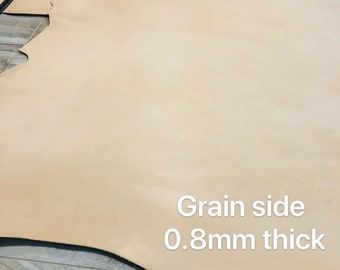 May include: A close-up of the grain side of a light brown leather hide. The leather is 0.8mm thick.