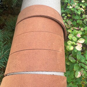 May include: A close-up of a brown leather wrapped around a gray cylinder. The leather is wrapped in multiple layers, creating a textured look.