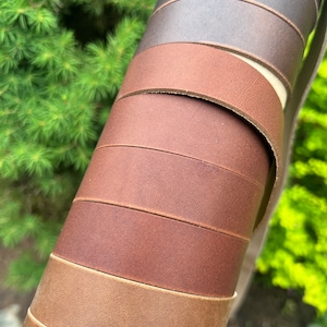 May include: A close-up of a roll of leather straps in various shades of brown, from light to dark.