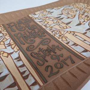 May include: A brown ceramic serving tray with a white and blue birch tree design. The tray is inscribed with the text "Amy & Andrew, September 9, 2017".