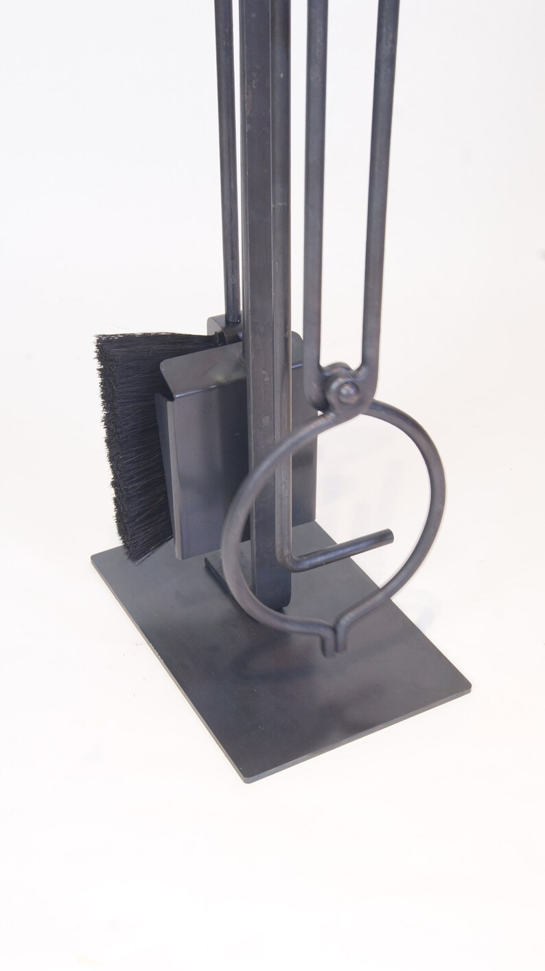 May include: A black metal fireplace tool set with a brush, poker, and tongs. The tools are attached to a black metal stand.