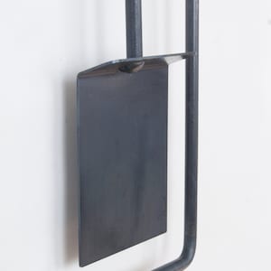 May include: A black metal fireplace tool set with a shovel, poker, and tongs. The tools are hanging on a wall mount.