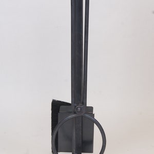 May include: Black metal fireplace tool set with a brush, poker, and shovel. The tools are attached to a stand with a circular base.