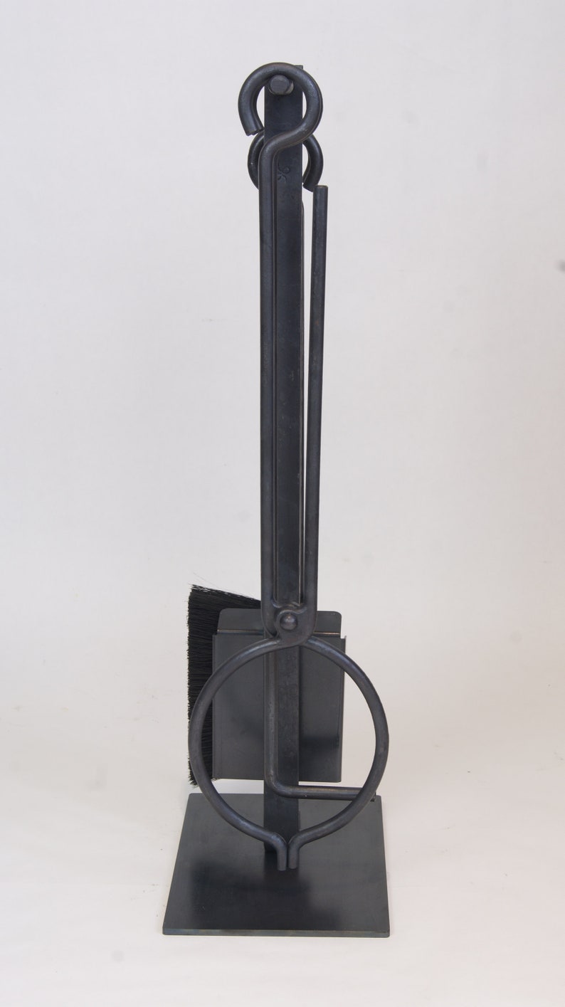 May include: Black metal fireplace tool set with a brush, poker, and shovel. The tools are attached to a stand with a circular base.
