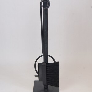 May include: Black metal fireplace tool set with a brush, poker, and shovel. The tools are attached to a stand with a black metal base.