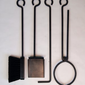 May include: A set of four black fireplace tools with a brush, shovel, poker, and tongs. The tools have a simple design with a loop at the top of each handle.