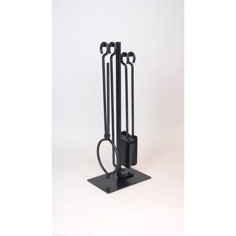 May include: Black metal fireplace tool set with a stand. The set includes a poker, shovel, tongs, and a brush.