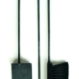 May include: A set of three fireplace tools with black metal handles and a black brush head. The tools include a shovel, poker, and brush.