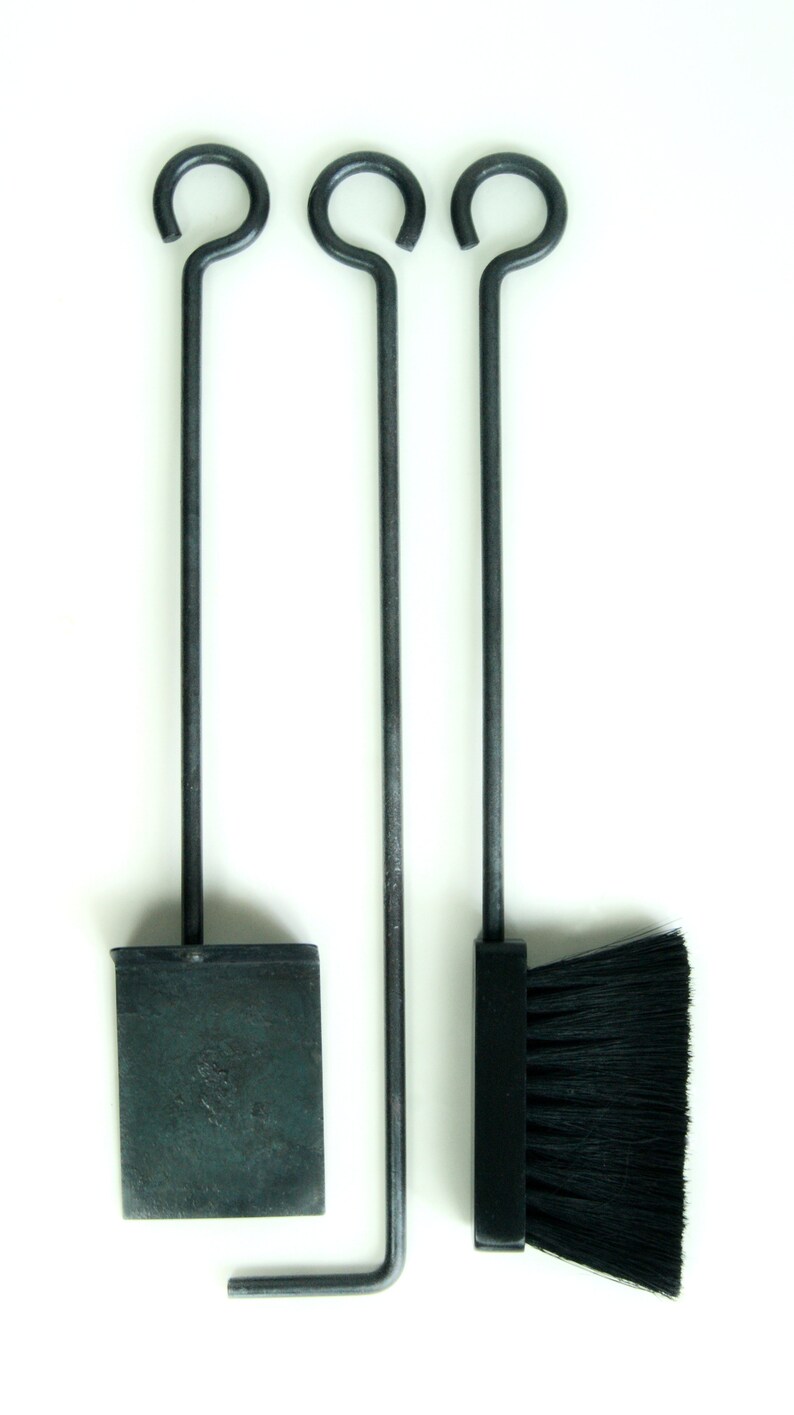 May include: A set of three fireplace tools with black metal handles and a black brush head. The tools include a shovel, poker, and brush.