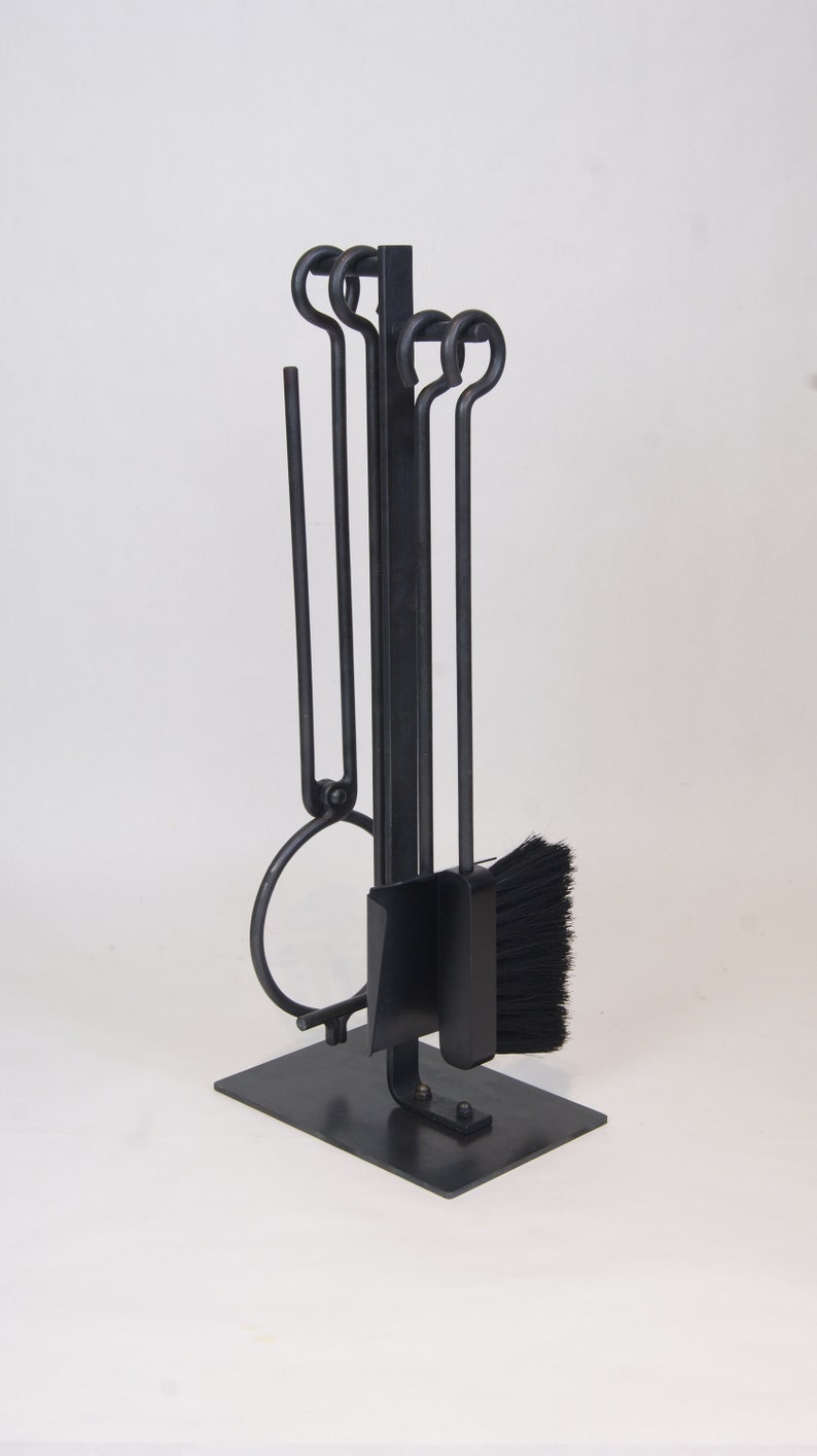 May include: Black metal fireplace tool set with a stand. The set includes a poker, tongs, brush, and shovel.