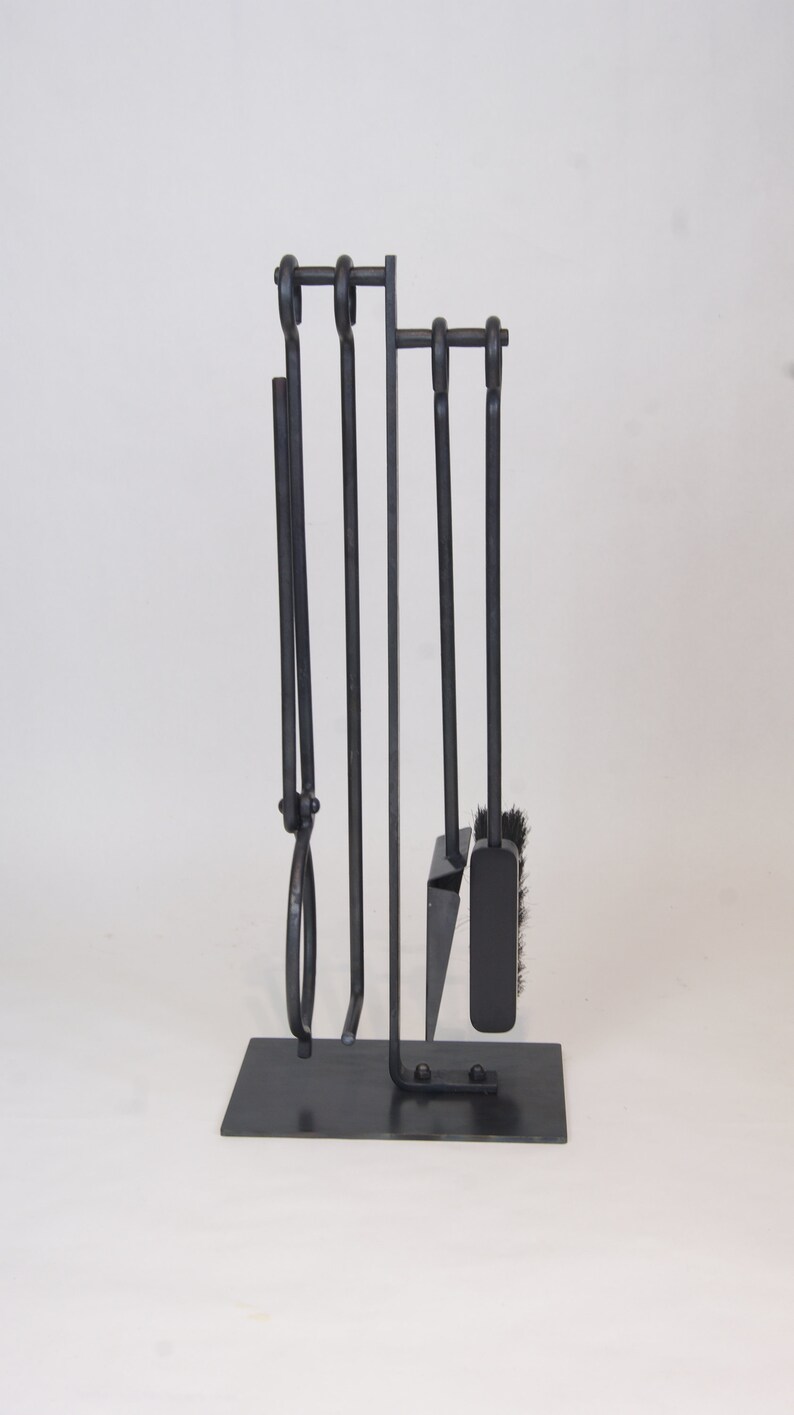 May include: A black metal fireplace tool set with a stand. The set includes a poker, shovel, tongs, and a brush.