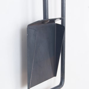 May include: A black metal fireplace tool set with a shovel, poker, and tongs. The tools are hanging on a wall.