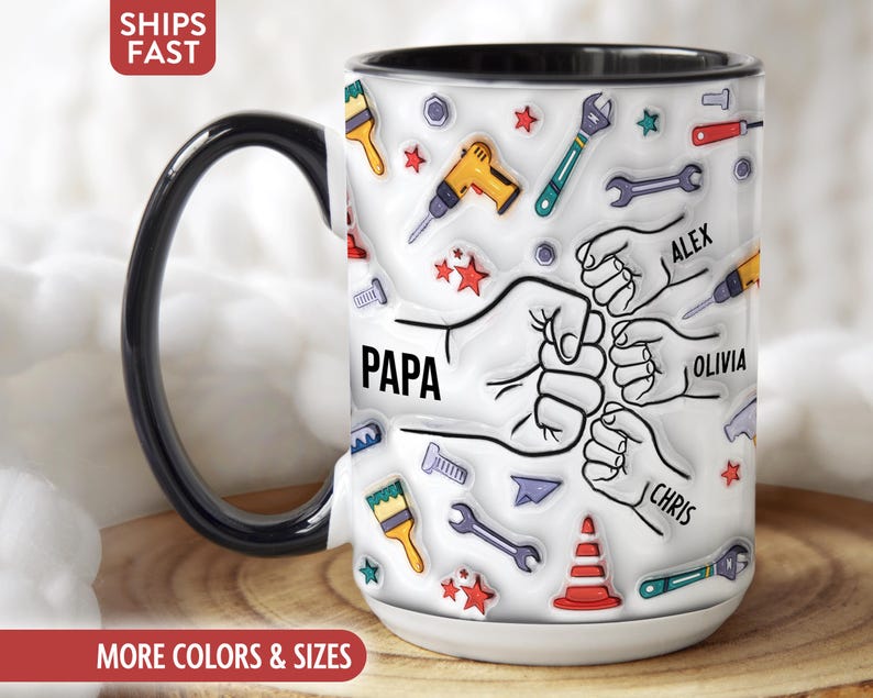 K&ouml;nnte beinhalten: Wei&szlig;er Keramikbecher mit schwarzem Henkel und Rand, verziert mit Werkzeugen, Sternen und dem Wort "PAPA". Der Becher enth&auml;lt Illustrationen von H&auml;nden und die Namen: Alex, Olivia und Chris. Ein Geschenk f&uuml;r einen Vater.