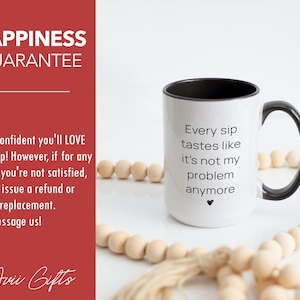 Puede incluir: Taza de caf&eacute; de cer&aacute;mica blanca con borde y asa negros. La taza tiene texto negro que dice "Every sip tastes like it's not my problem anymore". Un peque&ntilde;o s&iacute;mbolo de coraz&oacute;n est&aacute; debajo del texto. La taza est&aacute; sobre una superficie blanca con una guirnalda de cuentas de madera.