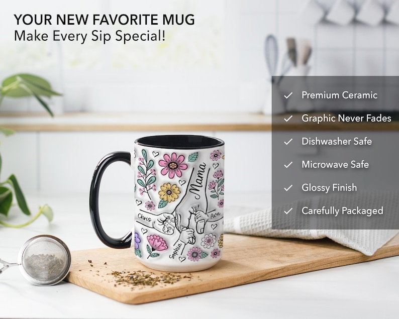 Op de afbeelding: Witte keramische mok met een zwarte handgreep en binnenkant, met een bloemenontwerp met het woord "Mama" en namen. De mok heeft ook de tekst "YOUR NEW FAVORITE MUG Make Every Sip Special!"