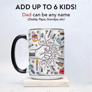 May include: White ceramic mug with a black handle and rim, featuring the word "DAD" and illustrations of tools and fists. The mug includes the text "ADD UP TO 6 KIDS!" and names like "ALEX" and "OLIVIA".