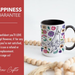 Puede incluir: Taza de cer&aacute;mica blanca con borde y asa negros. La taza presenta un dise&ntilde;o floral colorido con ilustraciones dibujadas a mano de manos que se sostienen. Los nombres "Chris", "Sophia", "Gigi" y "Aura" est&aacute;n escritos en las manos.