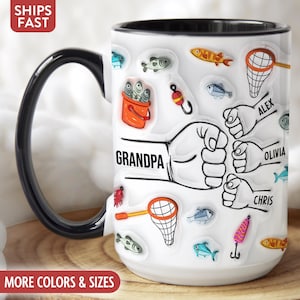 Peut inclure: Mug en céramique blanche avec une anse et un bord noirs, décoré d'illustrations sur le thème de la pêche. La tasse porte le mot "GRANDPA" et des noms personnalisés. Des poissons, des filets et des leurres sont dispersés.