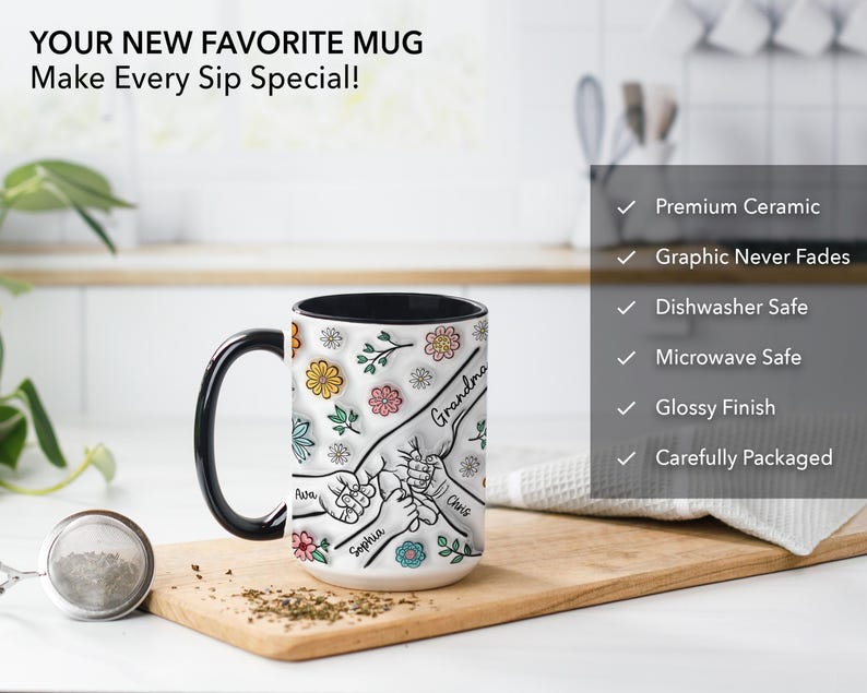 May include: White ceramic mug with a black rim and handle. The mug features a colorful illustration of five hands holding each other with the names "Grandma", "Awa", "Sophia", and "Chris" written on the hands. The mug is on a wooden surface.