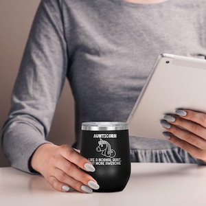 May include: Black stainless steel wine tumbler with a white unicorn graphic and the text "Aunticorn Like a normal aunt but more awesome".